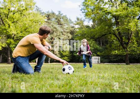 Man and boy playing with soccer ball on grass Stock Photo