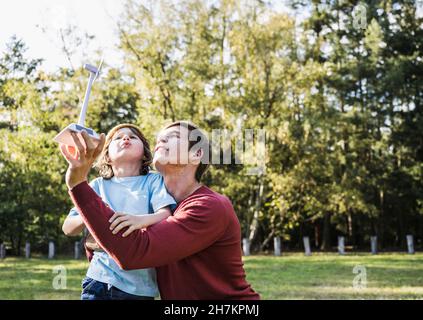 Man and boy looking at wind turbine model in park Stock Photo