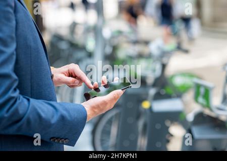 Young male professional using smart phone at bicycle parking station Stock Photo