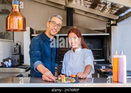 Smiling male and female chefs with tray at restaurant Stock Photo