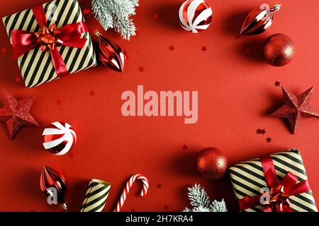Vintage Red Christmas background with red and white balls decoration, gift boxes, stars, fir tree branches in snow, candy cane, confetti. Retro Christ Stock Photo