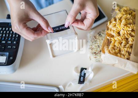 Top view woman hands sticking label marker on transparent plastic box with pasta Stock Photo