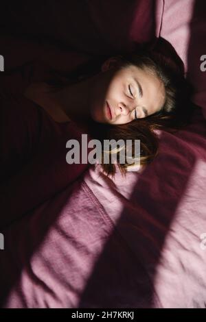 Depressed young woman with eyes closed lying on bed Stock Photo