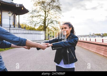 Happy young woman dancing with friend on footpath in park Stock Photo