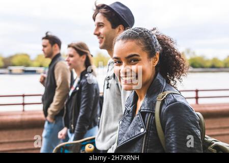 Young woman in leather jacket walking with friends Stock Photo