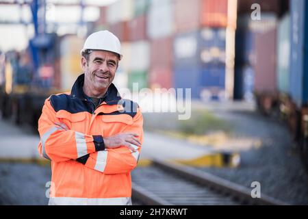 Happy male blue-collar worker with arms crossed in dock Stock Photo