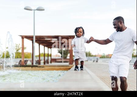 Girl holding hand of father walking by fountain Stock Photo