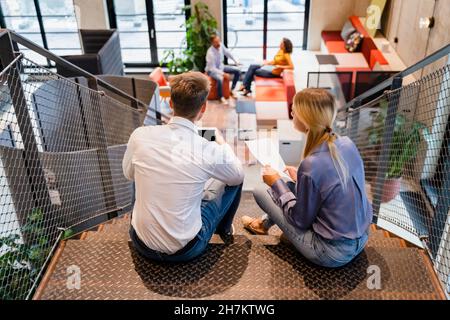 Young colleagues using tablet PC on office staircase Stock Photo