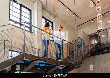 Coworkers having discussion at railing Stock Photo