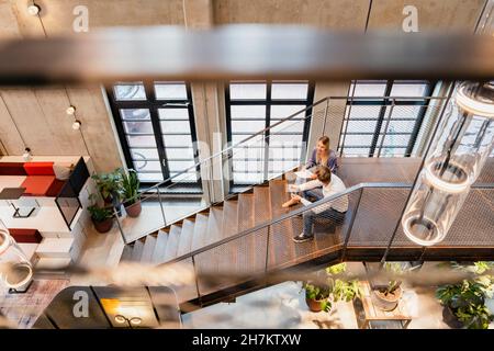 Coworkers having discussion at office staircase Stock Photo
