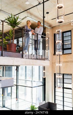 Coworkers having discussing at railing in office Stock Photo
