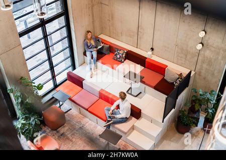 Young colleagues discussing while working at workplace Stock Photo