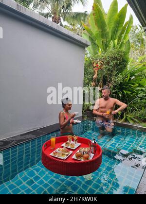 floating breakfast in plunge pool, afternoon tea or floating breakfast in swim pool. man and woman having breakfast in pool Stock Photo