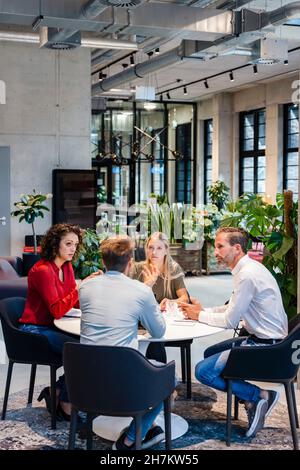 Colleagues having discussion while working at desk Stock Photo