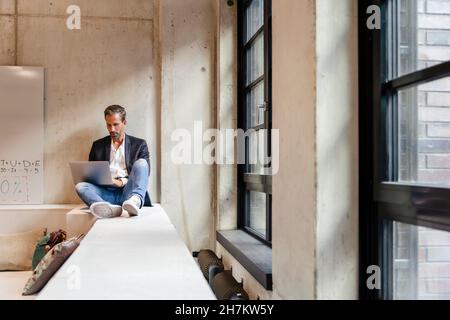 Businessman using laptop while sitting at workplace Stock Photo