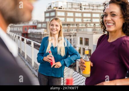 Blond businesswoman having drink with colleagues at rooftop Stock Photo
