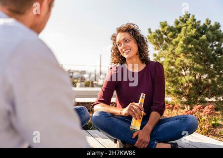 Smiling businesswoman having drink with colleagues on rooftop Stock Photo