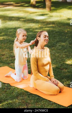 Girl brushing mother's hair in park Stock Photo