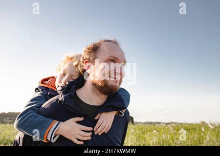Happy boy running in front of father on field Stock Photo
