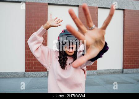 Woman screaming while using virtual reality headset on footpath Stock Photo