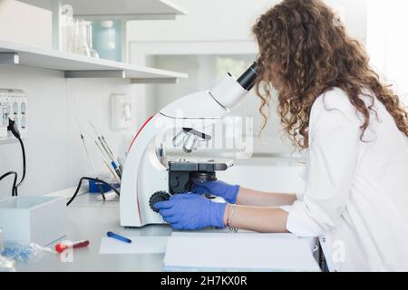 Young medical researcher using microscope in laboratory Stock Photo