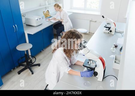 Woman researching through microscope in laboratory Stock Photo