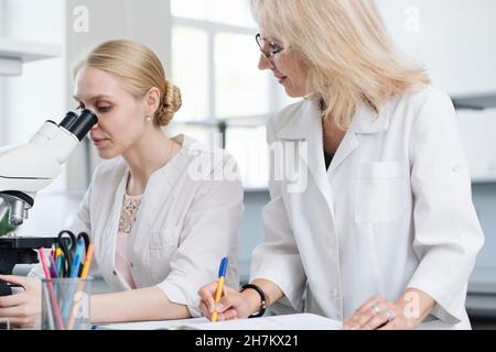 Scientists researching through microscope in laboratory Stock Photo