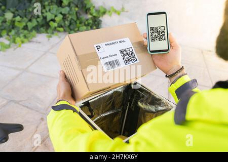 Delivery man scanning QR code through mobile phone Stock Photo