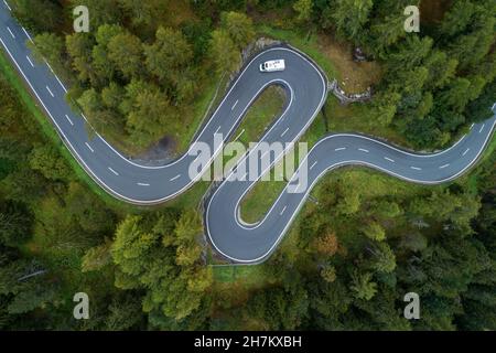 Drone view of single car driving along winding Maloja Pass road Stock Photo