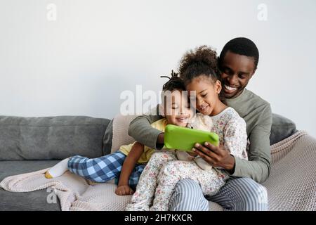 Smiling man with son and daughter using digital tablet on sofa Stock Photo