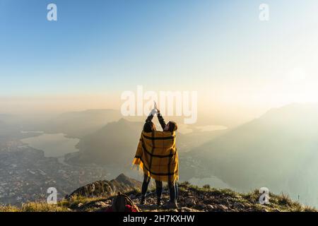 Young women doing high five on mountain peak at Orobie Alps, Lecco, Italy Stock Photo