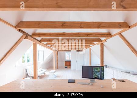 Home attic with computer monitor on wooden table in foreground Stock Photo