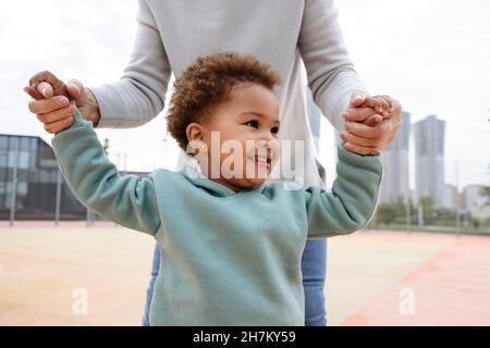 Cute girl holding hands of woman at sports field Stock Photo