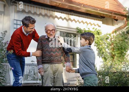 Smiling man with son consoling father in backyard Stock Photo