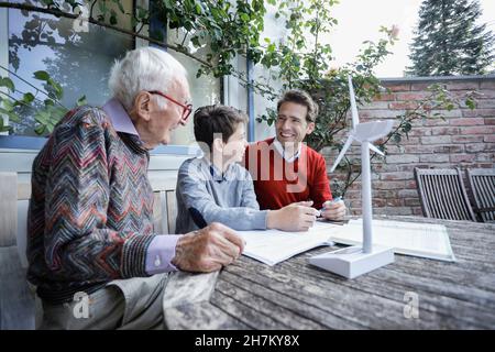 Smiling man looking at father by son studying in backyard Stock Photo