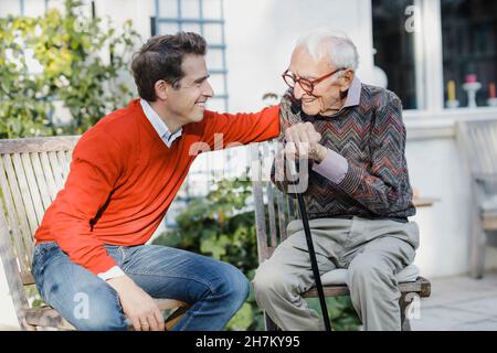 Happy man talking to elderly father in backyard Stock Photo
