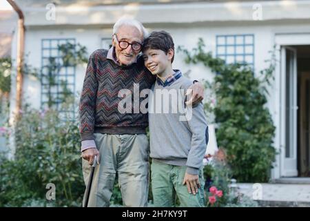 Smiling senior man embracing grandson at backyard Stock Photo