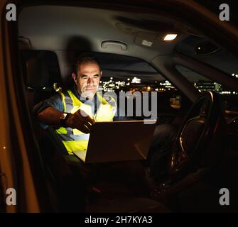 Engineer using laptop while working in car Stock Photo