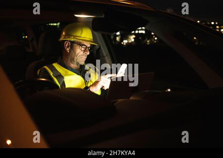 Engineer with hardhat using mobile phone in car Stock Photo