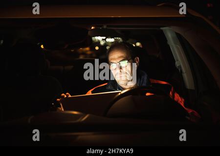 Engineer wearing eyeglasses using laptop in car Stock Photo