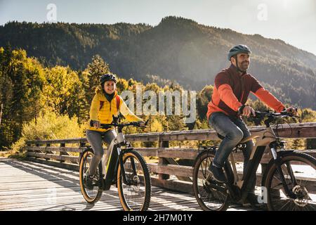 Woman riding bicycle with man on bridge Stock Photo