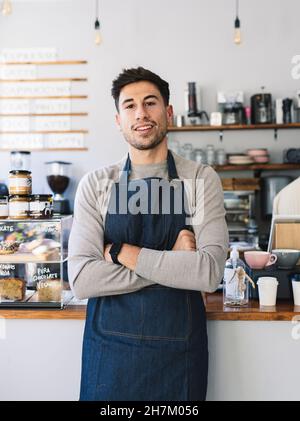 Man with apron using mobile phone in cafe Stock Photo