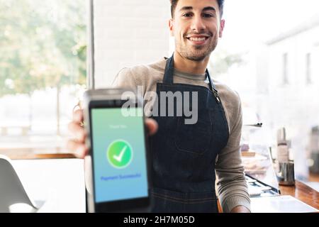 Waiter with check mark symbol on card reader screen in cafe Stock Photo