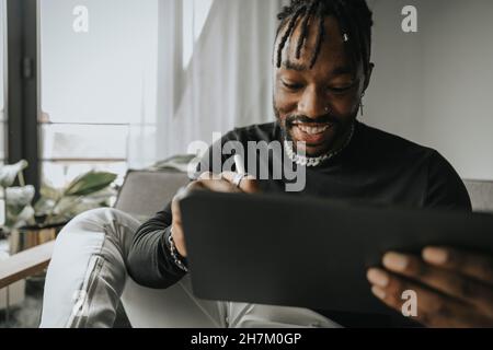 Smiling man using tablet PC at home Stock Photo