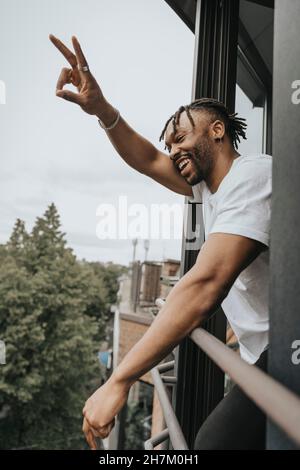 Man gesturing peace sign while leaning on railing Stock Photo