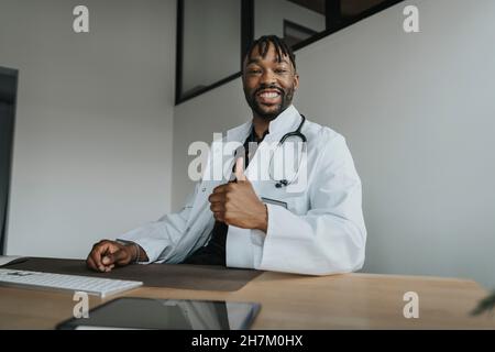 Young doctor gesturing thumbs up in office Stock Photo