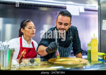 Chef teaching plating to student in restaurant kitchen Stock Photo