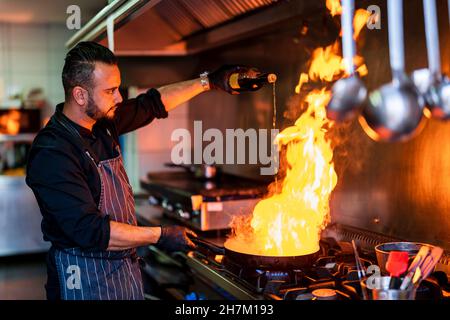 Chef preparing flambe dish on stove in restaurant kitchen Stock Photo