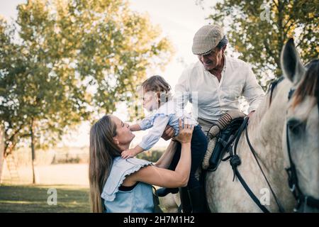 Father and daughter looking at horse in stable Stock Photo