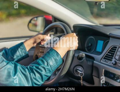 Closeup of a driver hands on steering wheel. Woman's hands holding steering wheel. Selective focus, concept photo new driver, blurred Stock Photo